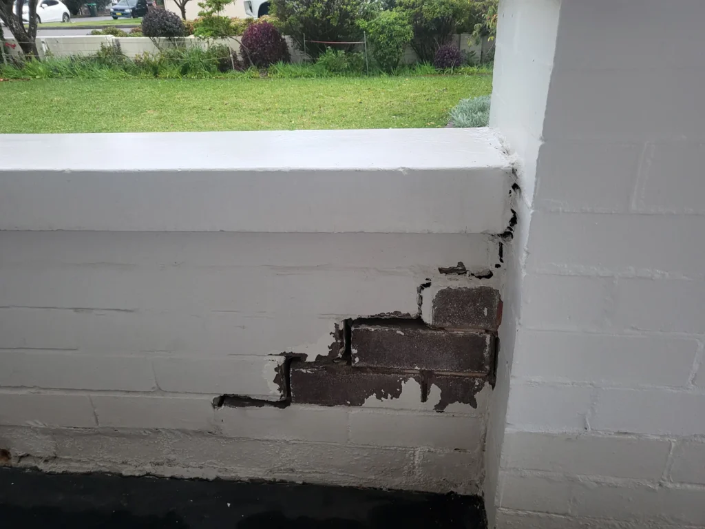 Brick wall fence showing cracks before repair